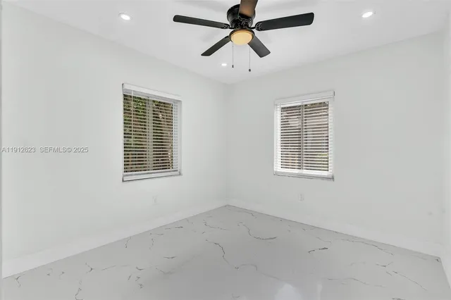 an empty room with windows and fan