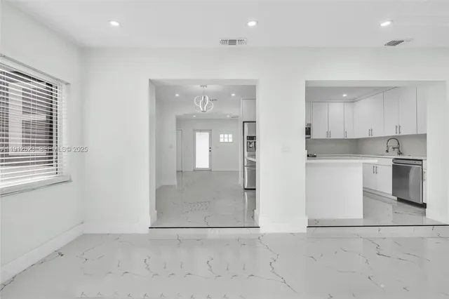an empty room with kitchen view and a window