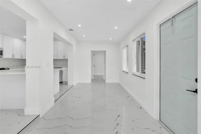 a view of empty room with kitchen and window