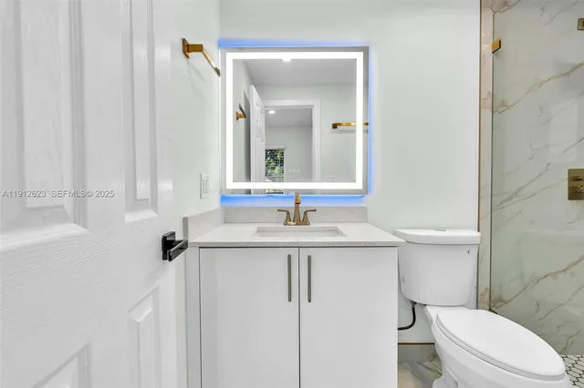a bathroom with a granite countertop sink toilet and mirror