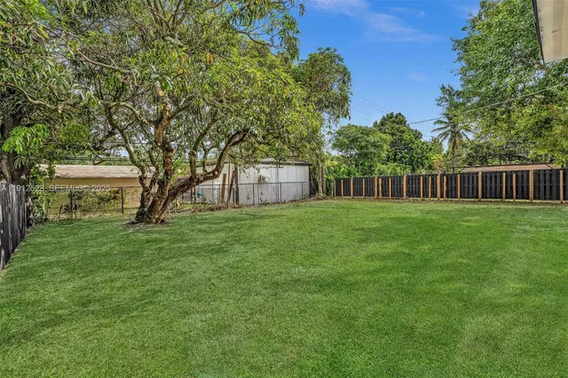 a view of a house with a big yard and large trees