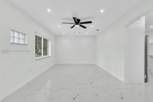an empty room with windows and ceiling fan