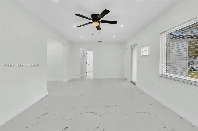 an empty room with ceiling fan and window