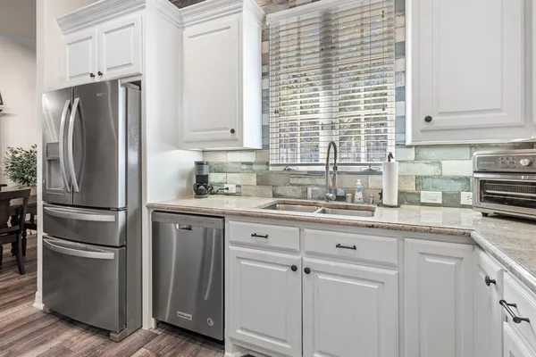 a kitchen with stainless steel appliances granite countertop white cabinets a sink and dishwasher
