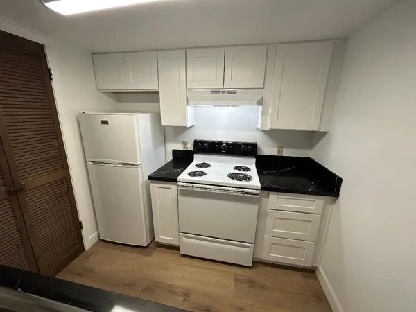 a kitchen with stainless steel appliances a refrigerator a stove and white cabinets