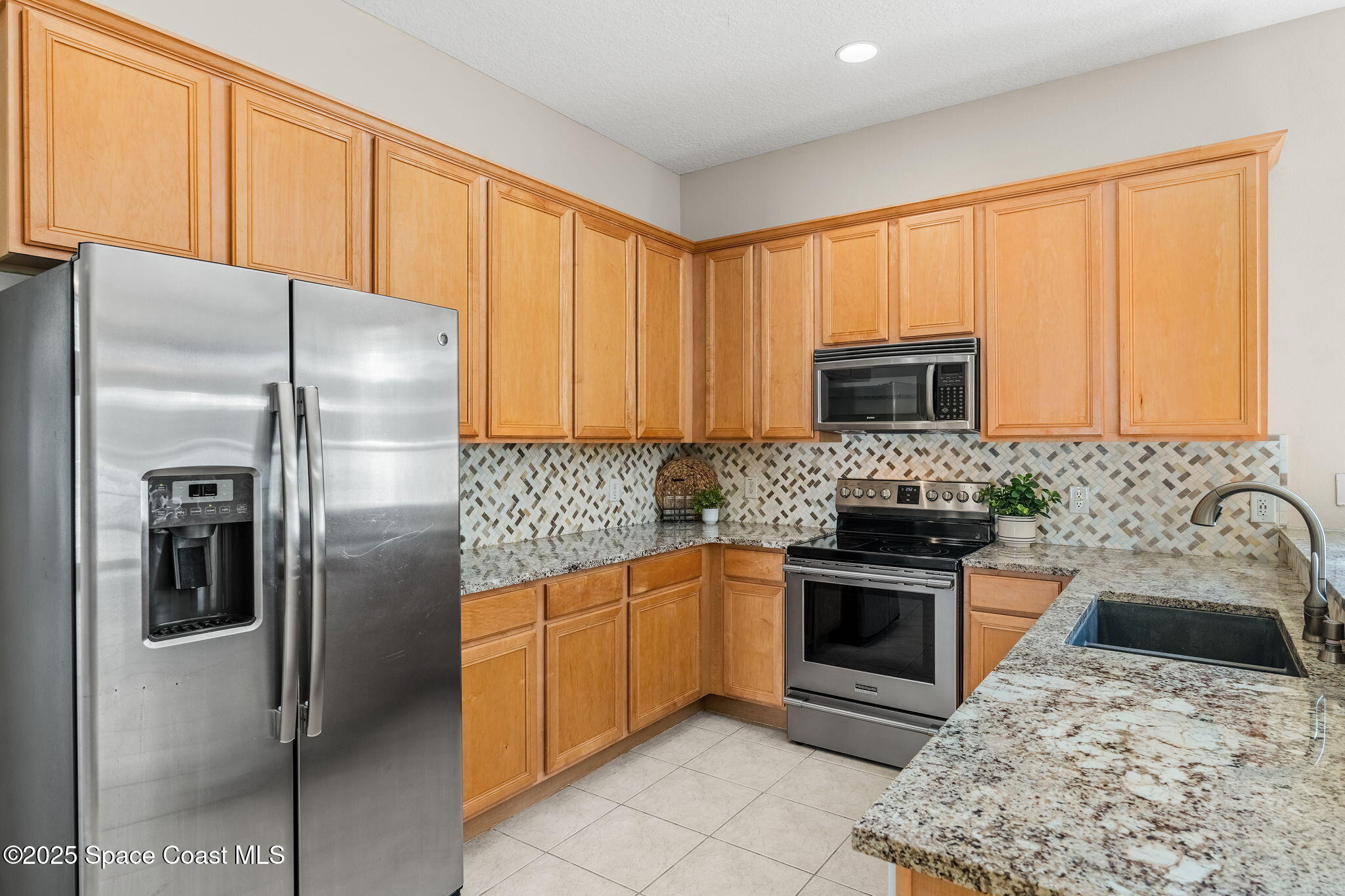 1908 Tullagee Avenue Melbourne, FL 32940 - Photo 11 of 58 a kitchen with stainless steel appliances granite countertop a refrigerator sink and stove