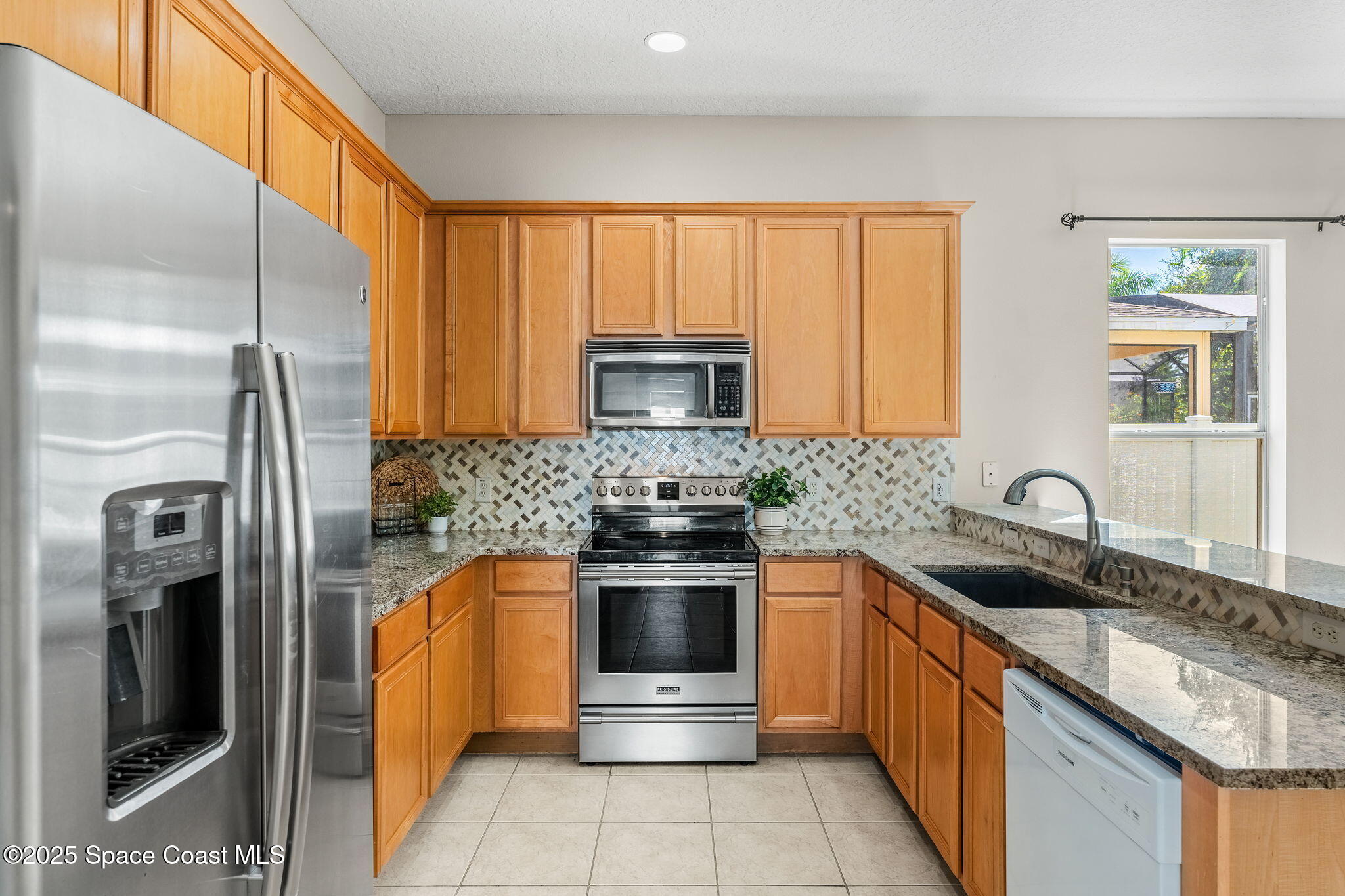 1908 Tullagee Avenue Melbourne, FL 32940 - Photo 10 of 58 a kitchen with stainless steel appliances granite countertop a sink stove and refrigerator