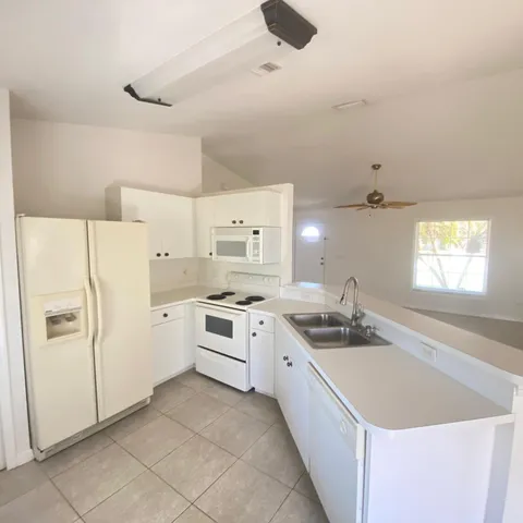 a kitchen with a sink a stove a refrigerator and white cabinets