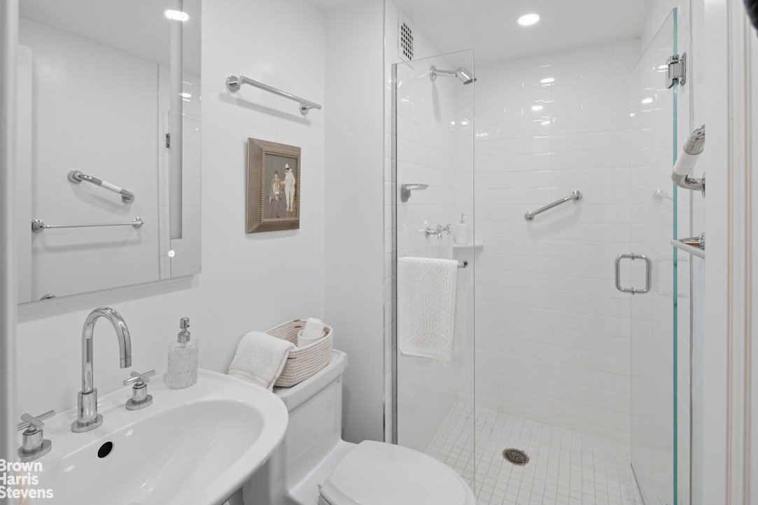 1050 5th Avenue, Unit 15C Manhattan, NY 10028 - Photo 11 of 15 a bathroom with a shower sink vanity mirror and toilet