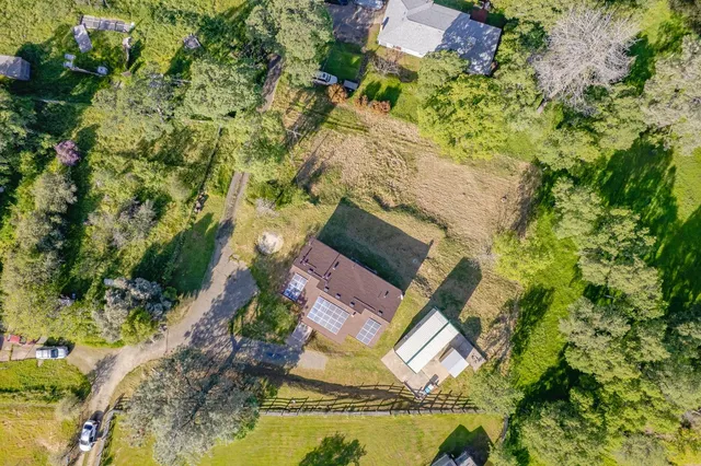 an aerial view of residential houses with outdoor space and trees