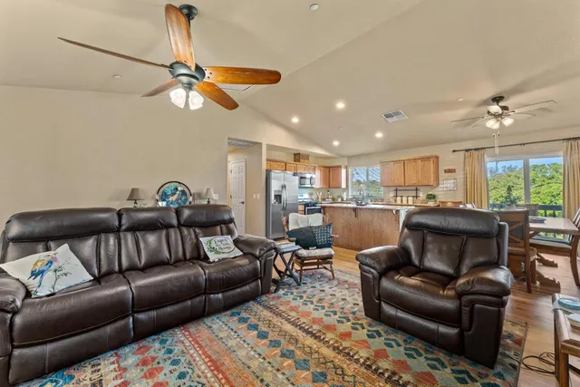 a living room with furniture kitchen view and a chandelier