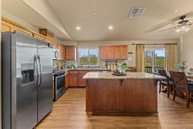 a view of a kitchen with kitchen island a large counter top stainless steel appliances and cabinets
