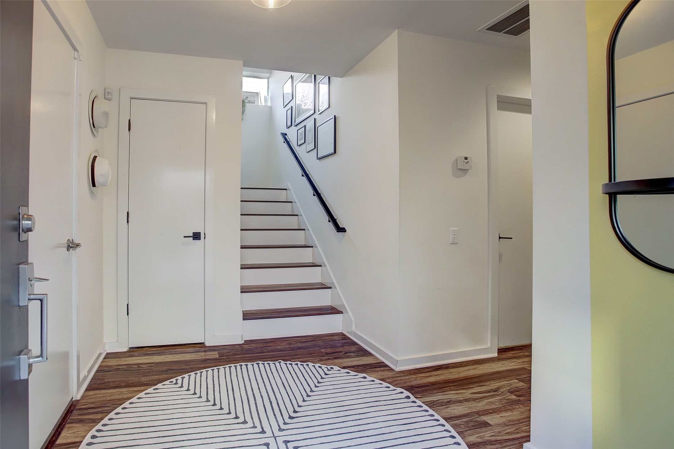 816 Ruthven Street Houston, TX 77019 - Photo 3 of 39 This photo showcases a modern, bright entryway featuring wooden flooring and staircase. The space is inviting and well-lit, with clean lines and a contemporary feel.