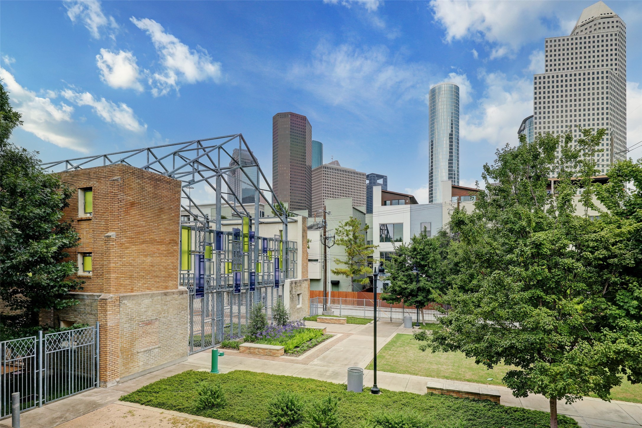 816 Ruthven Street Houston, TX 77019 - Photo 36 of 39 This photo showcases a modern urban setting with green spaces and contemporary architecture, set against a backdrop of city skyscrapers. Ideal for those seeking a vibrant downtown lifestyle with nearby amenities.