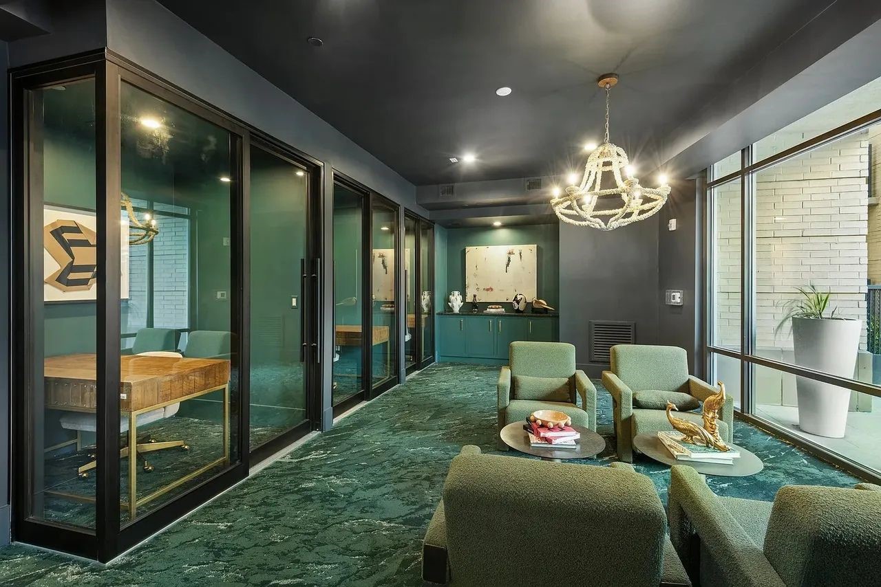 2724 Kipling Street, Unit 436 Houston, TX 77098 - Photo 4 of 29 A cozy mini lounge area with floor-to-ceiling windows flood the room with natural light and offer a seamless connection to the outdoor courtyard and pool area, giving the space an open, airy feel despite its dramatic interior palette. The textured carpeting adds depth and comfort underfoot, while the clean lines and curated décor maintain a polished, professional aesthetic.