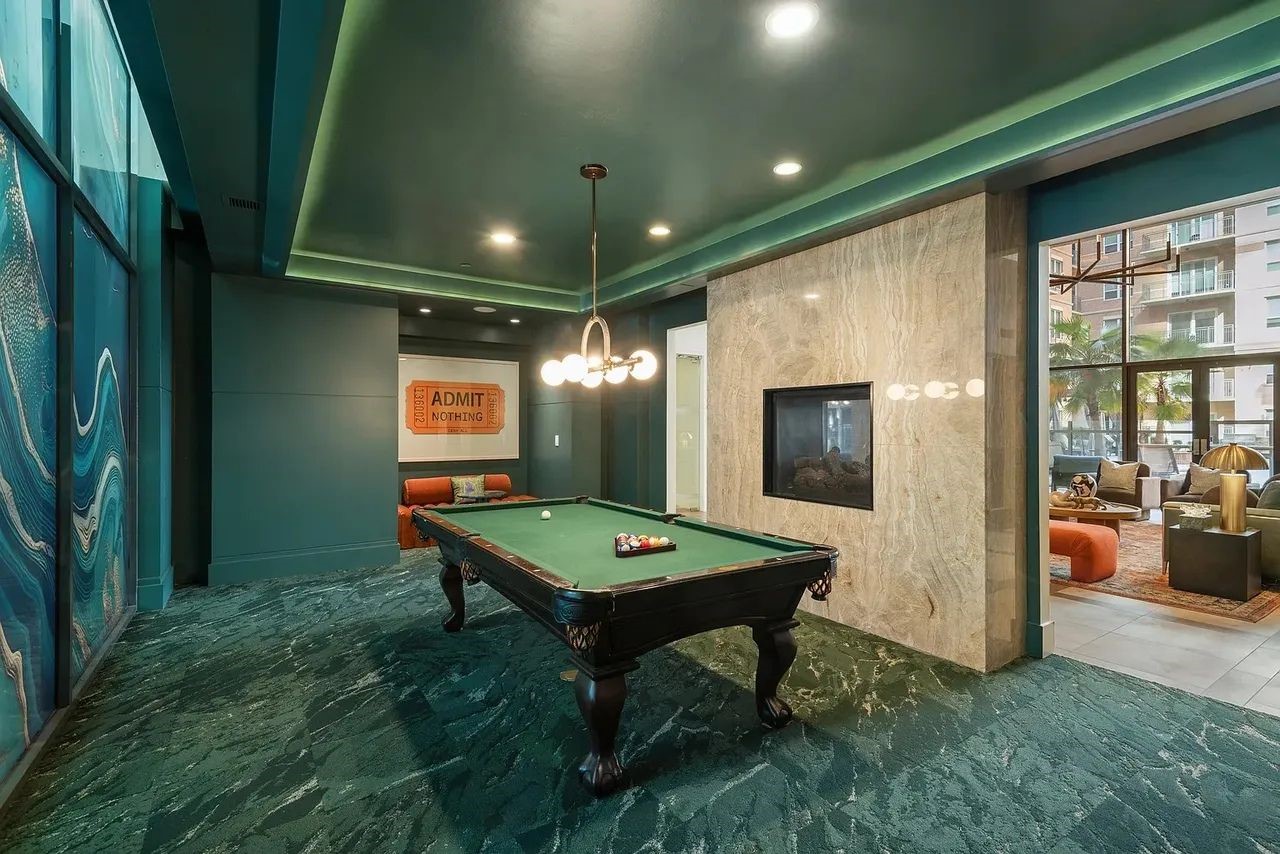 2724 Kipling Street, Unit 436 Houston, TX 77098 - Photo 5 of 29 The surrounding design details take it to the next level—custom wall paneling, a dramatic stone feature wall with a built-in fireplace, and contemporary lighting that adds warmth and ambiance. At the center, the classic pool table becomes both a functional amenity and a statement piece that is perfect for entertainment.