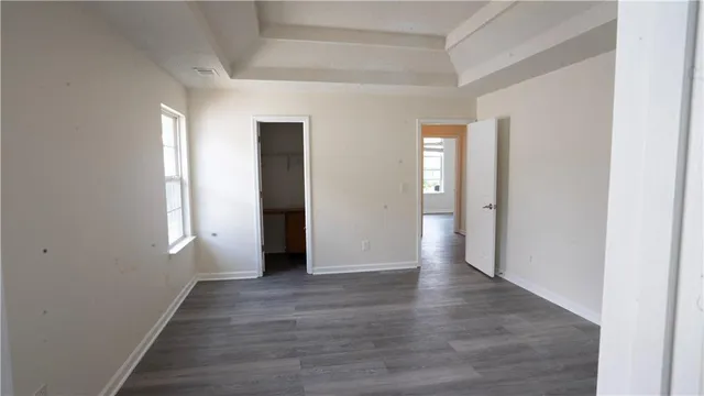 a view of an empty room with wooden floor and window