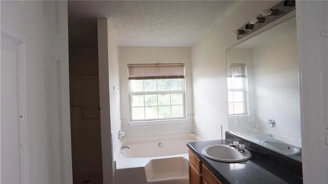 a bathroom with a granite countertop sink and a bathtub