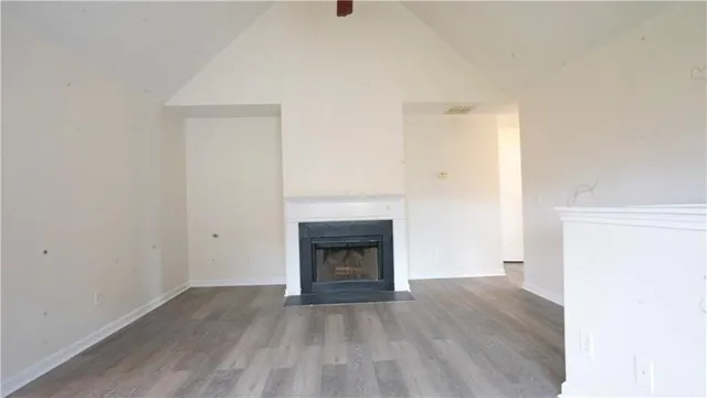 a view of an empty room with wooden floor fireplace and a window