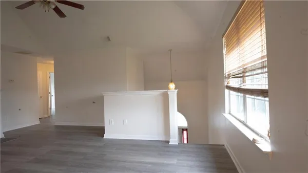 a view of an empty room with a window and wooden floor