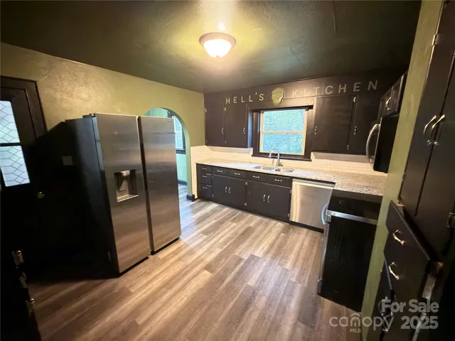 a kitchen with stainless steel appliances a refrigerator sink and wooden floor