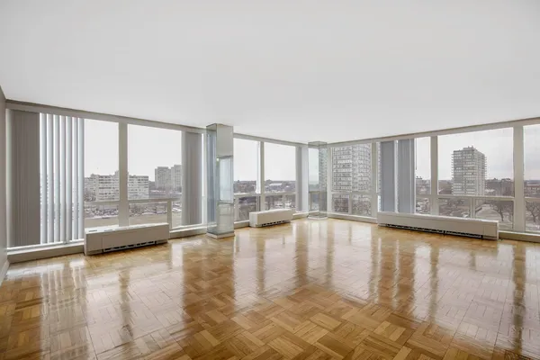 a view of empty room with floor to ceiling window and wooden floor