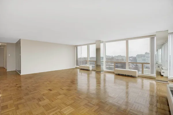 a view of an empty room with wooden floor and a floor to ceiling window