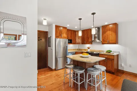 a kitchen with stainless steel appliances kitchen island a table chairs in it and wooden floors