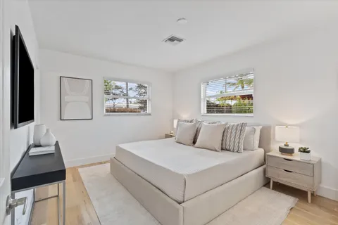 a bedroom with a large bed and a lamp on dresser