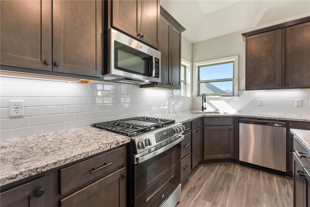 2813 Spector Drive Bryan, TX 77808 - Photo 18 of 42 a kitchen with granite countertop wooden cabinets and a stove top oven