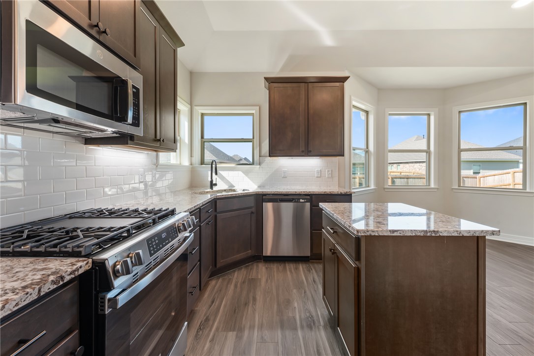 2813 Spector Drive Bryan, TX 77808 - Photo 19 of 42 a kitchen with granite countertop stainless steel appliances a sink stove top oven and microwave