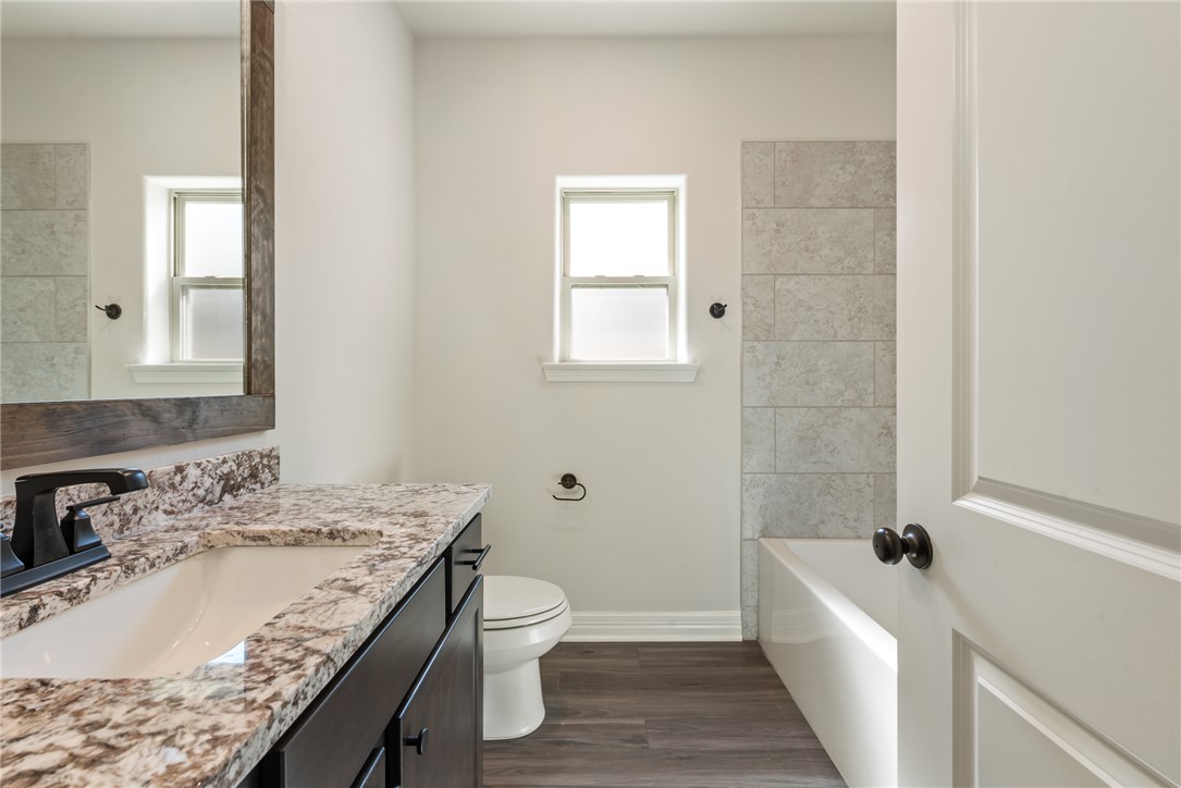 2813 Spector Drive Bryan, TX 77808 - Photo 37 of 42 a bathroom with a granite countertop sink a toilet and bathtub