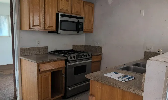 a kitchen with granite countertop cabinets stove top oven and microwave