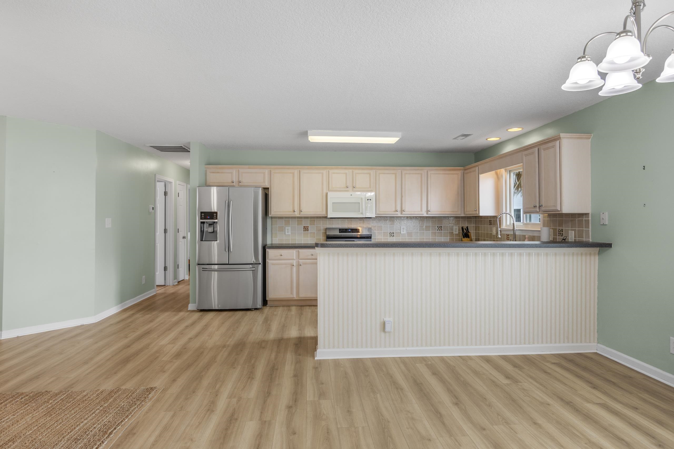 722 Downing Court Longs, SC 29568 - Photo 11 of 40 Kitchen with appliances with stainless steel finishes, a peninsula, a chandelier, hanging light fixtures, and backsplash