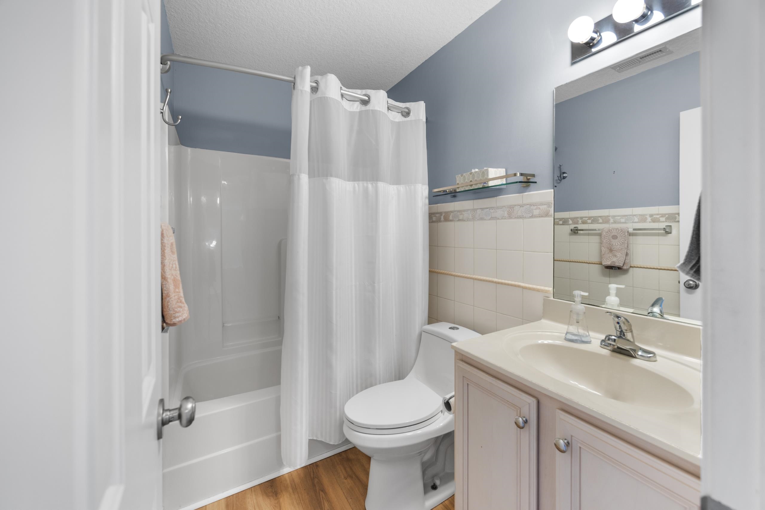 722 Downing Court Longs, SC 29568 - Photo 20 of 40 Bathroom featuring shower / bath combo, tile walls, vanity, light wood-type flooring, and a wainscoted wall