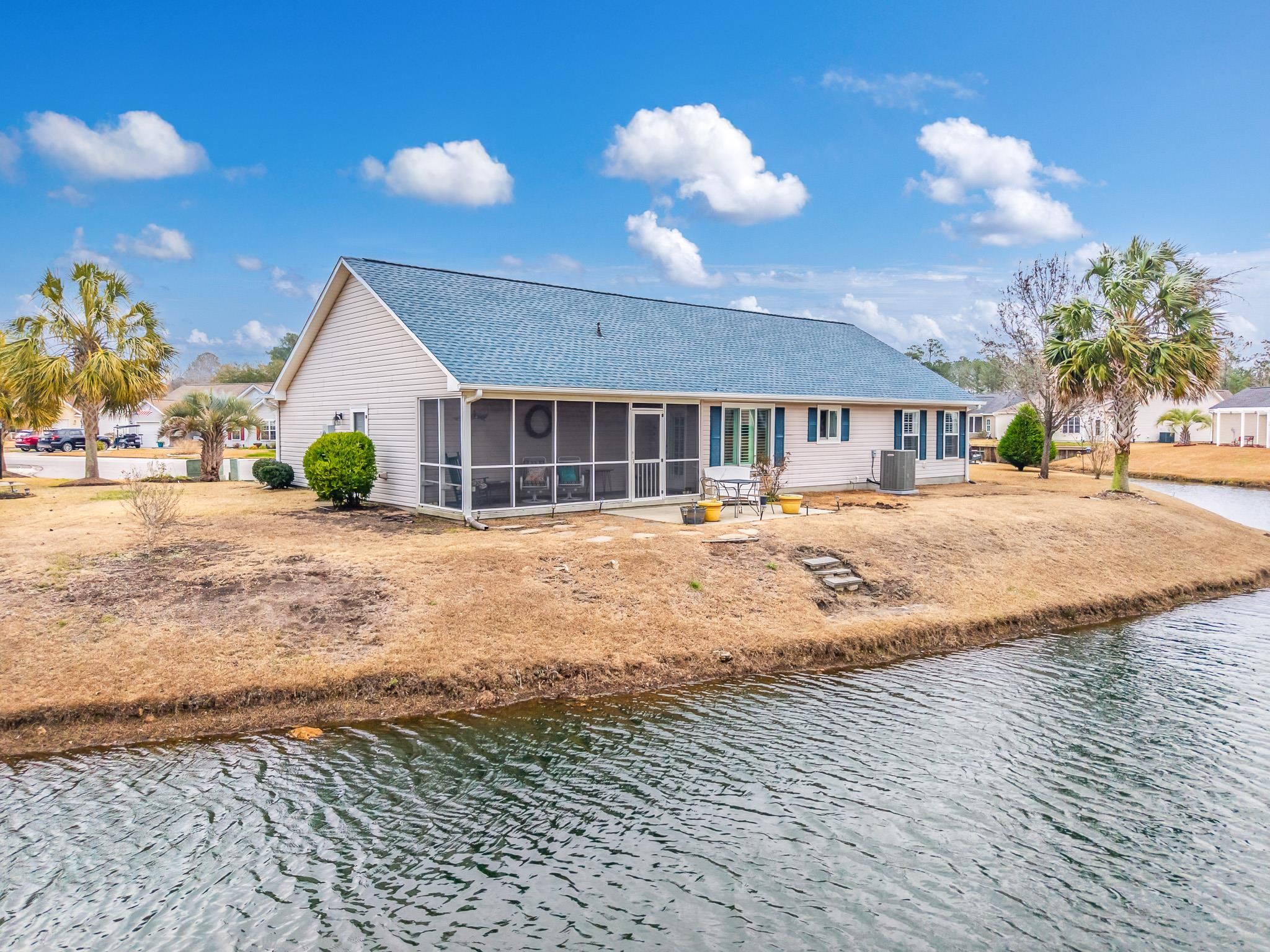 722 Downing Court Longs, SC 29568 - Photo 39 of 40 Back of house with a water view, a sunroom, and roof with shingles