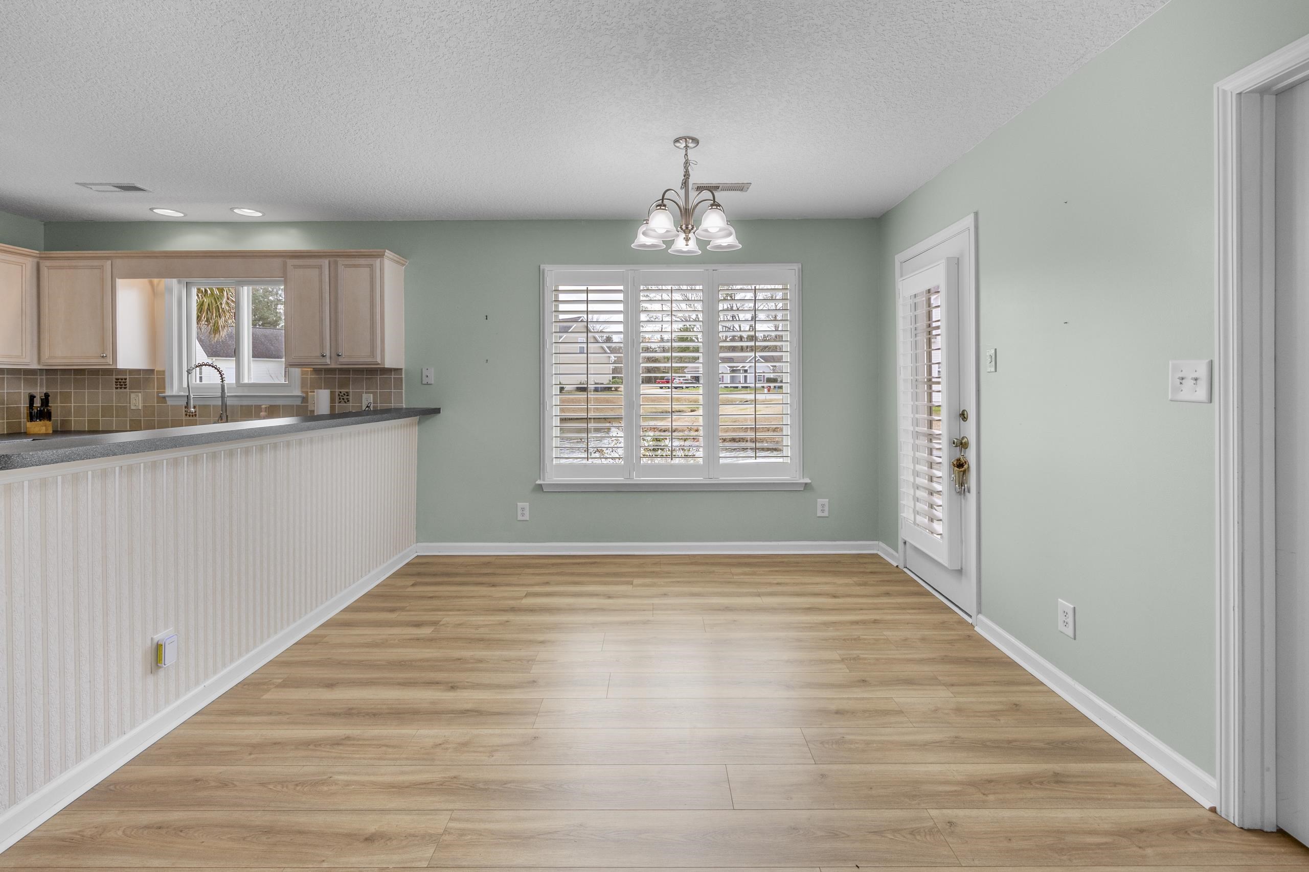 722 Downing Court Longs, SC 29568 - Photo 6 of 40 Unfurnished dining area featuring a chandelier, light wood-style floors, and a textured ceiling