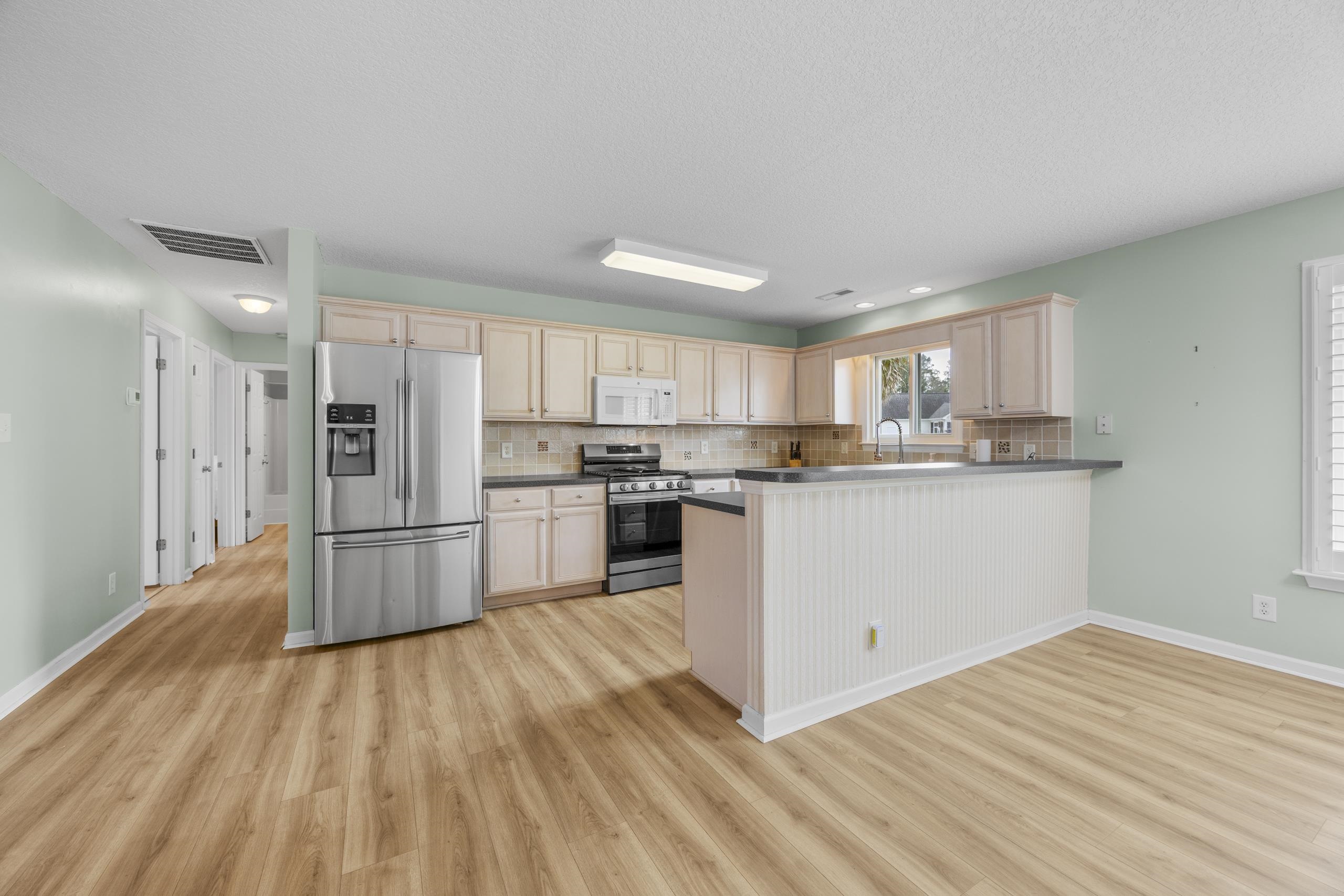 722 Downing Court Longs, SC 29568 - Photo 7 of 40 Kitchen featuring dark countertops, stainless steel appliances, a peninsula, and backsplash