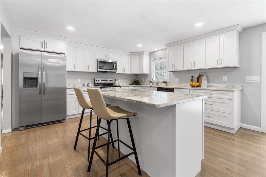 263 Great Road Shirley, MA 01464 - Photo 4 of 30 a kitchen with stainless steel appliances kitchen island granite countertop a refrigerator a stove a sink and white cabinets with wooden floor