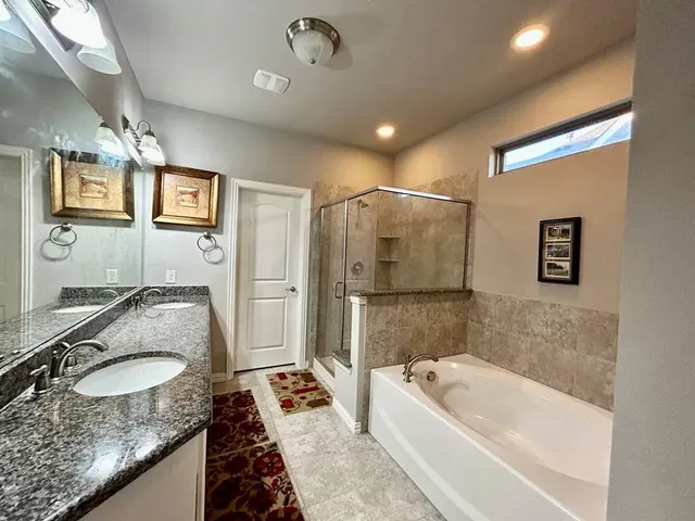 a bathroom with a granite countertop sink a mirror a bathtub and shower
