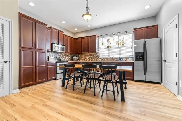 a kitchen with stainless steel appliances a dining table chairs refrigerator and cabinets