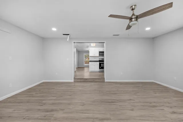 a view of empty room with wooden floor and ceiling fan