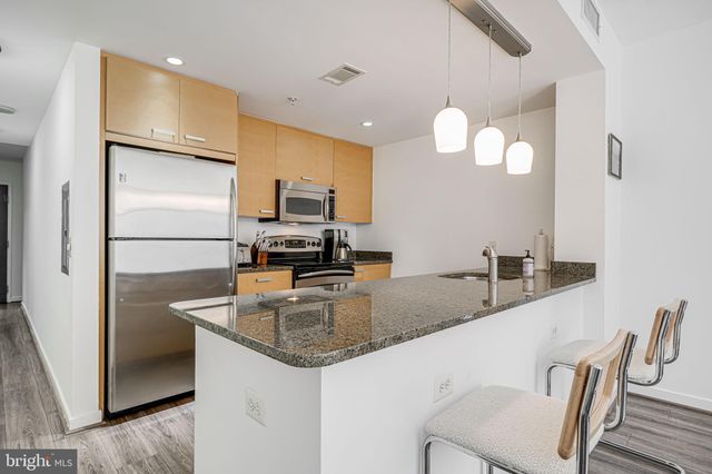 a kitchen with kitchen island granite countertop a sink a counter space appliances and cabinets