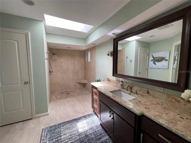 a bathroom with a granite countertop sink a mirror and a shower