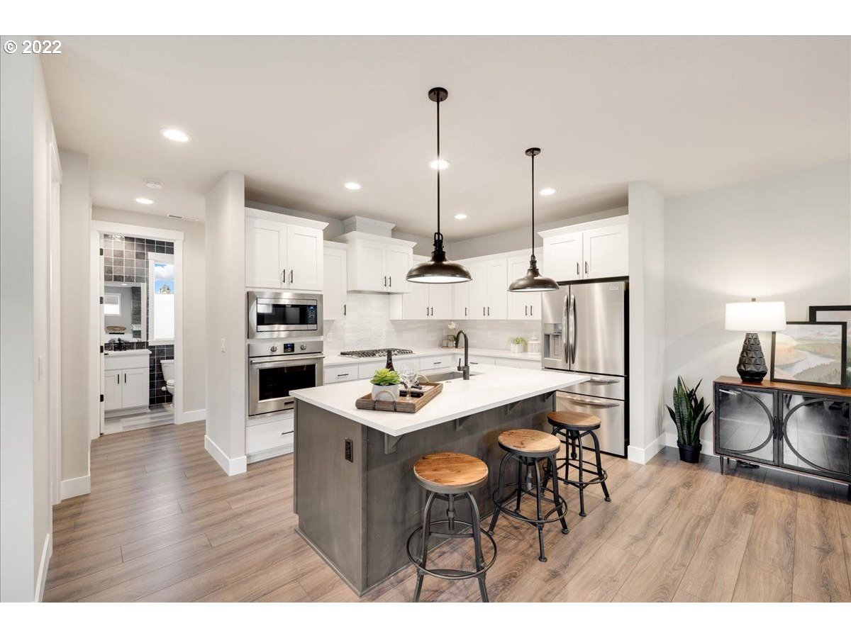 8534 North 5th Street, Unit LT 32 Ridgefield, WA 98642 - Photo 6 of 26 a kitchen with stainless steel appliances kitchen island granite countertop a table chairs stove and refrigerator