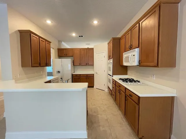 a kitchen with stainless steel appliances a stove a sink a refrigerator white cabinets and wooden cabinets