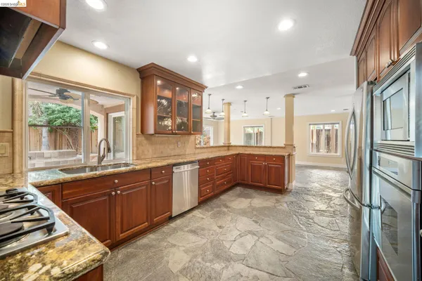 a large kitchen with stainless steel appliances granite countertop a sink and cabinets