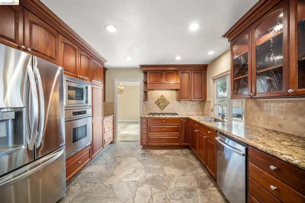 a large kitchen with stainless steel appliances granite countertop a refrigerator and a stove top oven