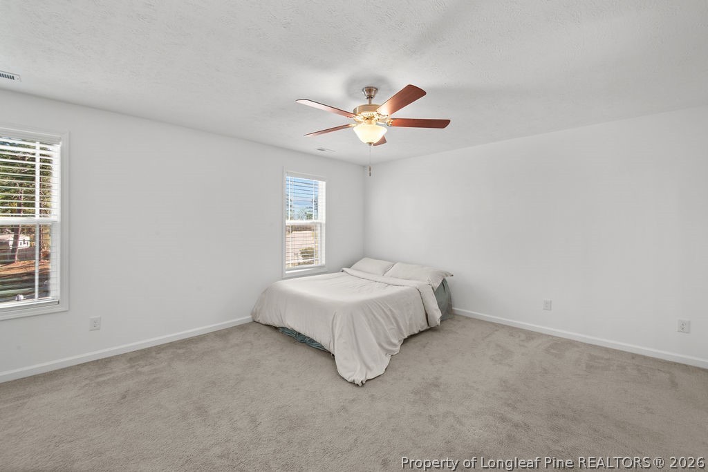 6915 Wickersham Road Fayetteville, NC 28314 - Photo 17 of 25 a spacious bedroom with a bed and a chandelier fan