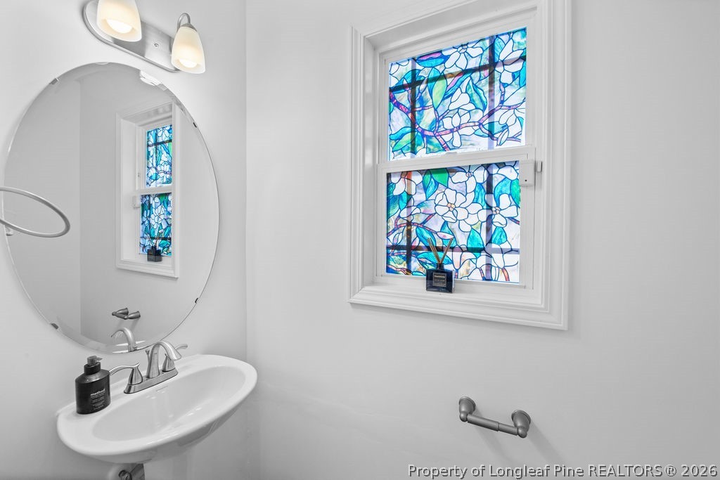 6915 Wickersham Road Fayetteville, NC 28314 - Photo 8 of 25 a bathroom with a sink a mirror and a window